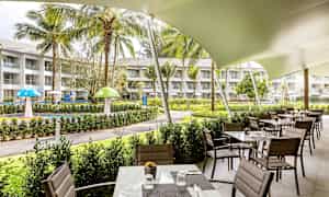 Restaurant med uteservering ved en hage med gressområder og lekeområde. (AI-generert tekst)