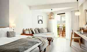 Lyse og moderne hotellrom med seng, sittemøbler og utgang til balkong. (AI-generert tekst)