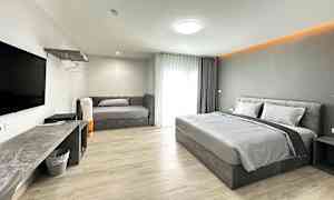 Et hotellrom med en dobbeltseng, en sofa og en TV på veggen. (AI-generert tekst)