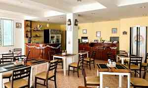 Et bilde av en liten restaurant eller kafé med bord og stoler, en bardisk og interiør inkludert pyntegjenstander og dekorasjoner. (AI-generert tekst)