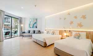 Rom med to senger, en sofa og et bord nær et stort vindu med utsikt. (AI-generert tekst)