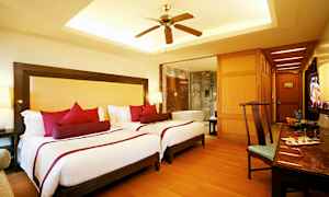 Et hotellrom med to enkeltsenger, en vifte og et badekar i bakgrunnen. (AI-generert tekst)