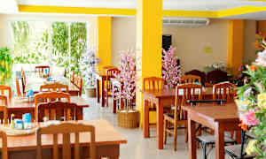 Restaurant med trebord og stoler samt dekorative blomster. (AI-generert tekst)