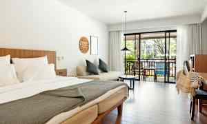 Et hotellrom med en dobbeltseng, sofa og balkong med utsikt. (AI-generert tekst)