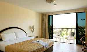 Et hotellrom med en dobbeltseng, nattbord, glassdører og en balkong med stoler. (AI-generert tekst)