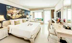 Et lyst og elegant hotellrom med en stor seng, sittegruppe ved vinduet og et skrivebord med stol. (AI-generert tekst)