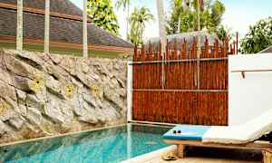 Et privat basseng med solseng ved siden og steiner pynter veggen bak bassenget. (AI-generert tekst)