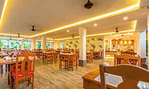 Bilde av en lys restaurant med trebord og stoler. (AI-generert tekst)