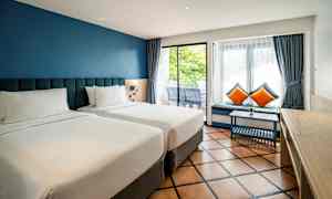 To enkeltsenger på et hotellrom med blå vegger og store vinduer. (AI-generert tekst)