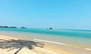 Sandstrand med klart blått hav og noen små øyer i bakgrunnen. (AI-generert tekst)