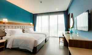 Hotellrom med to enkeltsenger, skrivebord, TV og store vinduer. (AI-generert tekst)