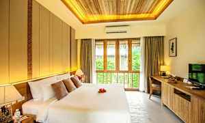 Et soverom med en stor dobbeltseng, dekorative puter og en sengelampe. Et stort vindu med gardiner slipper inn naturlig lys. (AI-generert tekst)