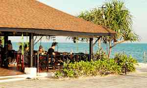 Et utendørsområde med en trebaldakin ved sjøen, omgitt av grøntområder. (AI-generert tekst)