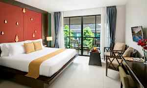 Et hotellrom med en stor seng og utgang til en balkong med utsikt til grøntområder. (AI-generert tekst)