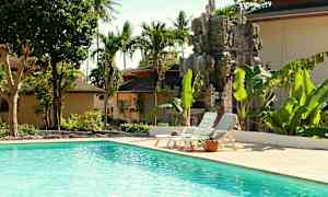 Utendørsbasseng omgitt av tropiske trær og en dekorativ steinstatue. (AI-generert tekst)