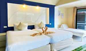 Bilde av et hotellrom med to enkeltsenger, en dekorativ håndklekunst i hjerteform og en dagseng ved siden av. (AI-generert tekst)