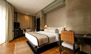 Et hotellrom med en stor oppredd seng, skrivebord med stol og en TV i et koselig og lyst innredet rom. (AI-generert tekst)