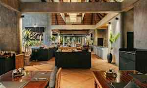 Interiørbilde av en restaurant med rustikk innredning, trebord og en bufféstasjon i midten. (AI-generert tekst)