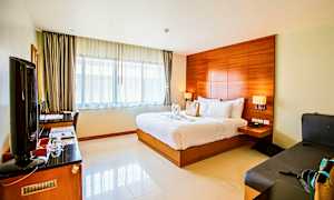 Et hotellrom med en dobbeltseng, skrivebord, TV og sittemøbler. (AI-generert tekst)