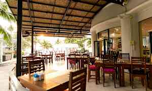 En utendørs restaurant med tak og trebord som står på en stor terrasse. (AI-generert tekst)