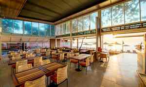 En restaurant med utsikt over stranden, innredet med bord og stoler. (AI-generert tekst)