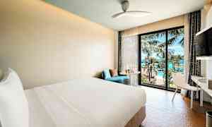 Moderne hotellrom med utsikt over hav og palmer gjennom et vindu. (AI-generert tekst)