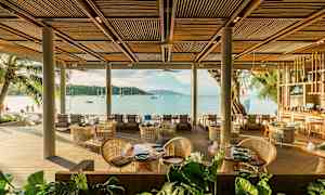 En restaurant ved stranden med sitteplasser og utsikt over havet. (AI-generert tekst)