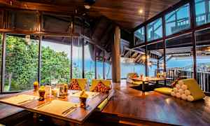 En restaurant med vakker utsikt over havet, med treinteriør og store vinduer. (AI-generert tekst)