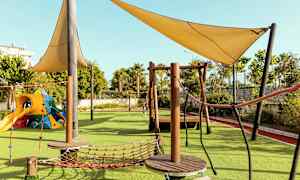 Lekeplass med klatreutstyr og skyggegivende seil. (AI-generert tekst)