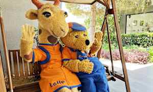 To figurer i kostymer, en giraff og en bjørn, sitter på en huske og vinker. (AI-generert tekst)