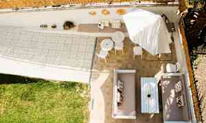 Oversikt over en uteplass med sittegrupper, bord, parasoll og gressplen. (AI-generert tekst)