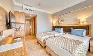 Hotellrom med to enkelsenger, et skrivebord og en dør til badet. (AI-generert tekst)