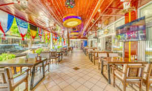 Restaurant med trebord og stoler samt fargerike flagg hengende fra taket. (AI-generert tekst)