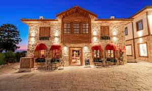 En steinbygning med røde markiser og sittemøbler på et steinbelagt torg. (AI-generert tekst)