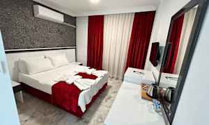 Et hotellrom med en dobbeltseng, hvit og rød innredning samt et skrivebord med speil. (AI-generert tekst)