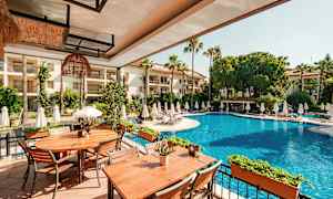 Bilde av et utendørsbasseng med solsenger rundt og bord på en terrasse. (AI-generert tekst)