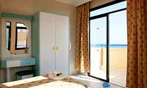 Et soverom med en åpen balkongdør som viser havutsikten. (AI-generert tekst)