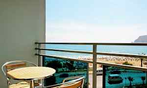 Balkong med et bord og to stoler, utsikt mot stranden og havet. (AI-generert tekst)