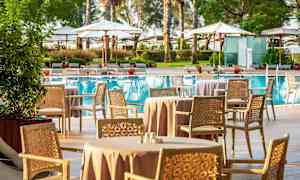 Utendørsområde med sittegrupper og spisebord ved et basseng. (AI-generert tekst)