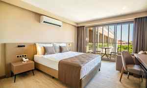 Et hotellrom med en stor seng, nattbord og en balkong med utsikt. (AI-generert tekst)