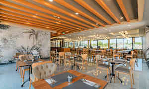 En moderne restaurant med store vinduer, tremøbler og dekorative takbjelker. (AI-generert tekst)