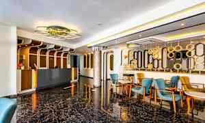 Lobby med resepsjon, blå og gule stoler og moderne innredning. (AI-generert tekst)