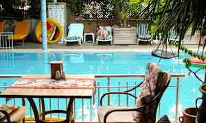 Et svømmebasseng med solsenger og en sittegruppe i forgrunnen. (AI-generert tekst)