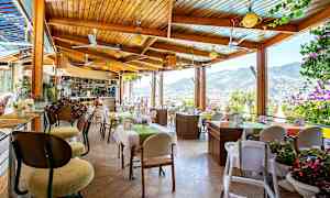 En restaurant med utsikt over fjellene og byen, med bord dekorert med blomster. (AI-generert tekst)