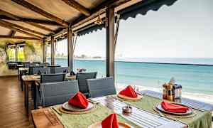 Restaurant med havutsikt, bord med røde servietter. (AI-generert tekst)