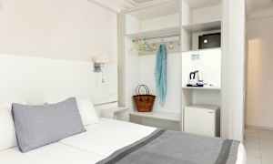 Hotellrom med seng, garderob og en minikjøleskap. (AI-generert tekst)