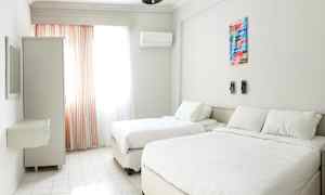 Et lyst hotellrom med to senger, et vindu med gardiner og en garderobe. (AI-generert tekst)