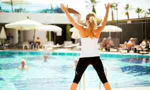 Person står foran et basseng og holder armene opp. (AI-generert tekst)