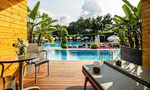 Terrasse foran et basseng med solsenger, bord og planter. (AI-generert tekst)