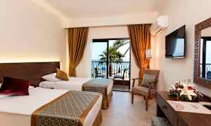 Hotellrom med to enkeltsenger, vindu med utsikt mot palmer og hav. (AI-generert tekst)